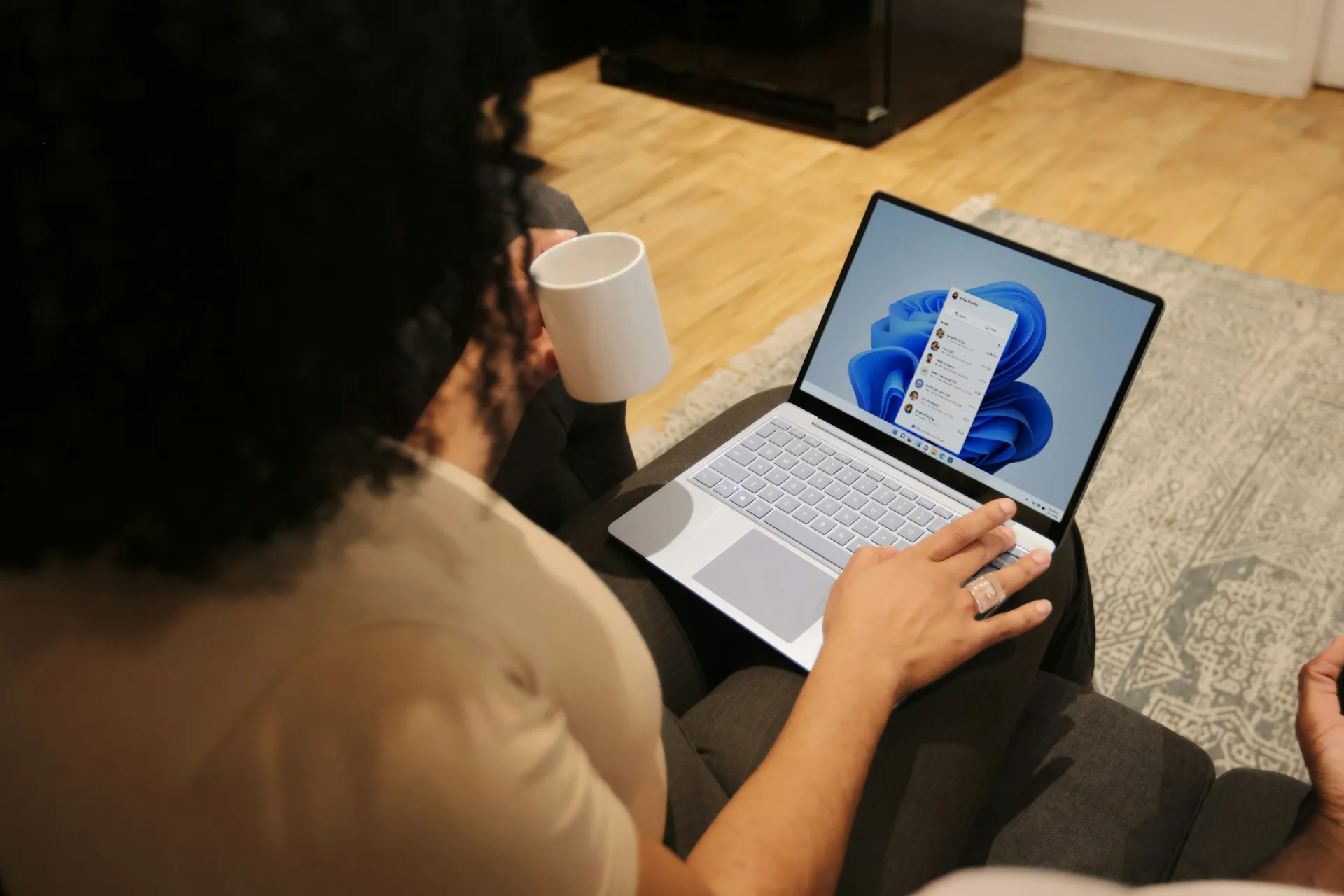 Person holding a coffee mug while working on a Windows laptop